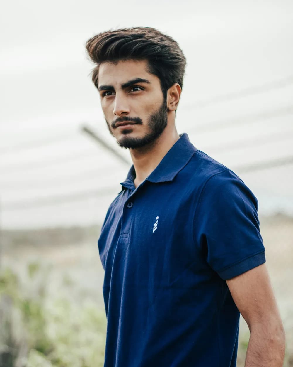 A man in a navy pique polo shirt outdoors
